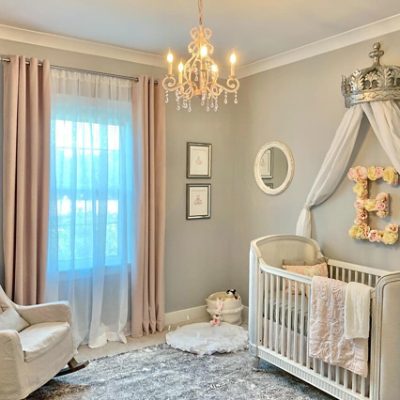 A neutral toned nursery with a chandelier 
