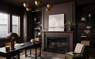 A dark study color-drenched in Sherwin-Williams Chateau Brown with a desk, built-in shelves, fireplace, large landscape painting, and houseplants.