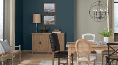 Dining room painted in dark blue with a table and chairs, buffet, chandelier.