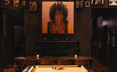 Stylish restaurant interior with a pool table, eclectic wall art, and cozy seating. 
