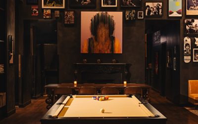 Stylish restaurant interior with a pool table, eclectic wall art, and cozy seating. 