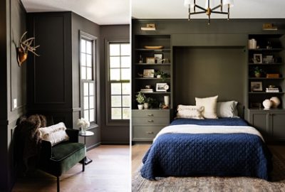 A stylish bedroom featuring a dark green chair with a white blanket, a small table with a flower, and a bed topped with a deep-blue quilt and flanked by built-in shelves.