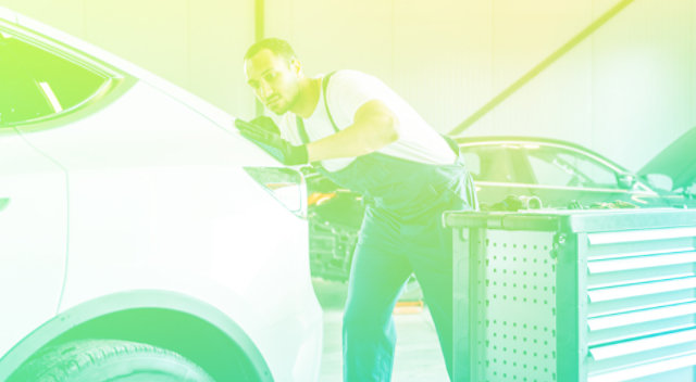 Automotive technician at auto service center, servicing a car.