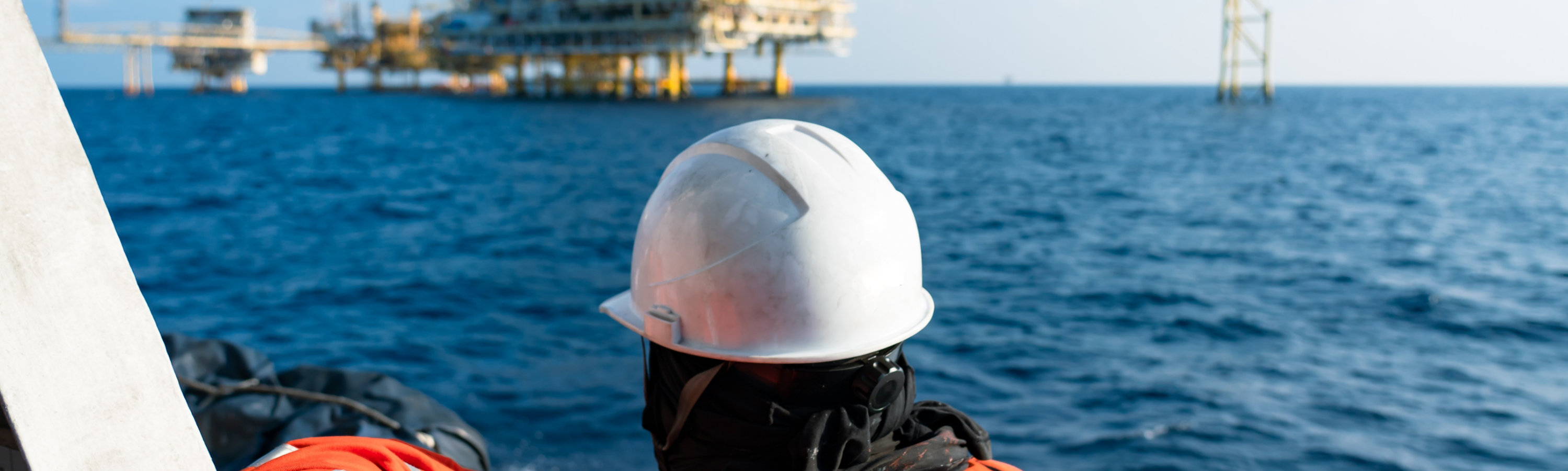 oil worker looks out onto a rig at sea