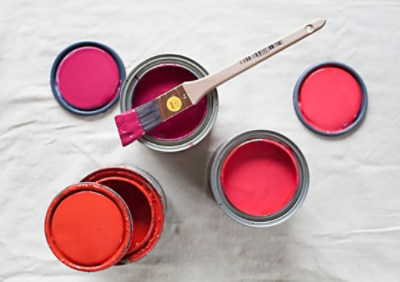 Open cans of red and pink paint and a paint brush