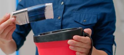 A person holding a paint brush and paint can.