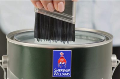 Paint brush dipping into a gallon of Sherwin-Williams paint.