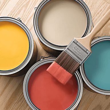 Paint brush resting on 4 paint cans.