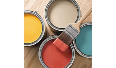 Paint brush resting on 4 paint cans.