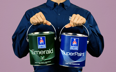 A person in a dress shirt with the Sherwin-Williams logo holding two cans of paint.