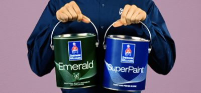 Person holding up Emerald and SuperPaint paint cans.