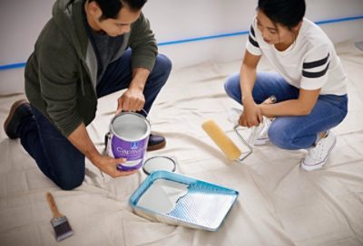 Two people pouring paint inside a paint tray.