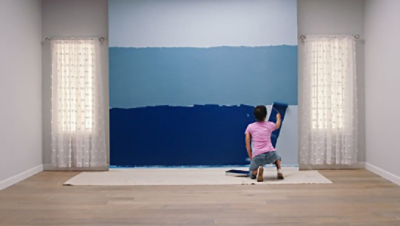 A woman painting the bottom section of a blue ombre wall 