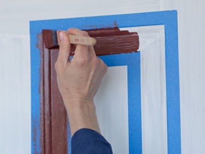 A person painting a front door with a brush.