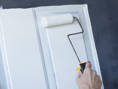 A person priming a front door for painting.