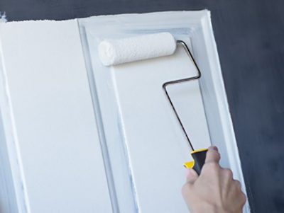 A person painting a front door with a roller.