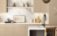 Marble backsplash with beige cabinets and neutral kitchenware.