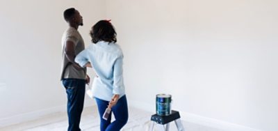 A couple standing in a freshly painted room, admiring their work.
