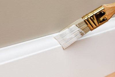 A person painting the trim with a small paint brush.