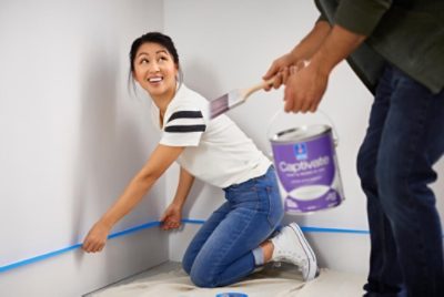 A person applying painter's tape on the trim.