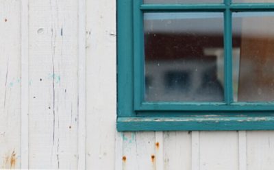 An outdoor windowsill with blue paint peeling.