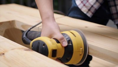 A person sanding a picnic table.