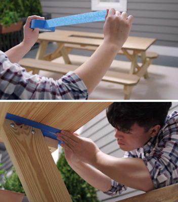 A person taping off a picnic table before painting.
