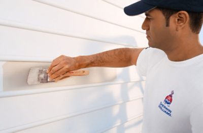 Un contratista de pintura pintando el exterior de una casa.