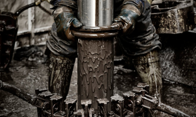 rigworker pulling muddy drill out of earth