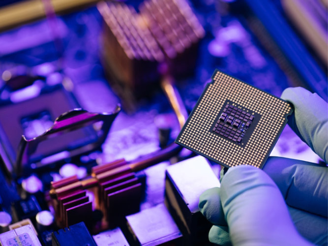 Person holding a microchip from a circuit board.