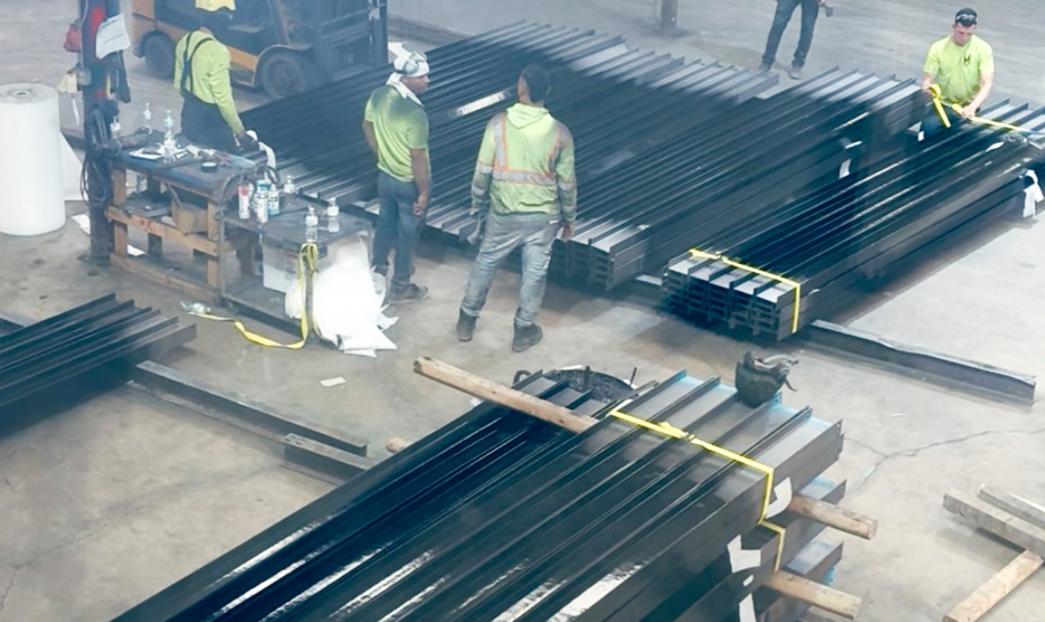 Bundles of black-coated steel piles in a fabrication facility.