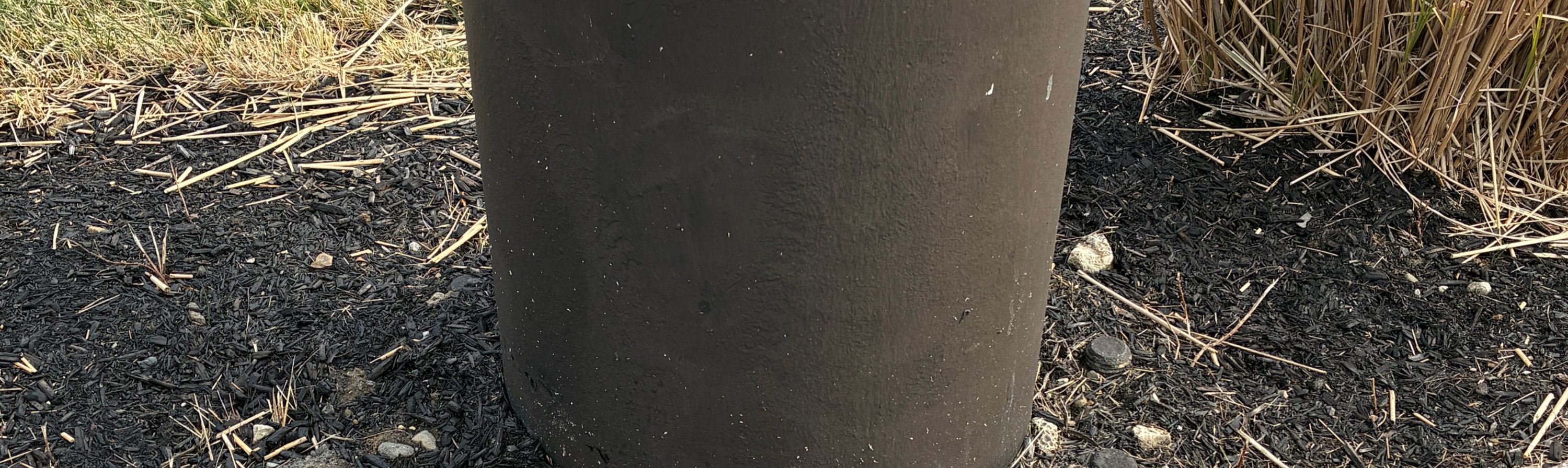 Structural support with a dark protective coating applied at and below the ground line.
