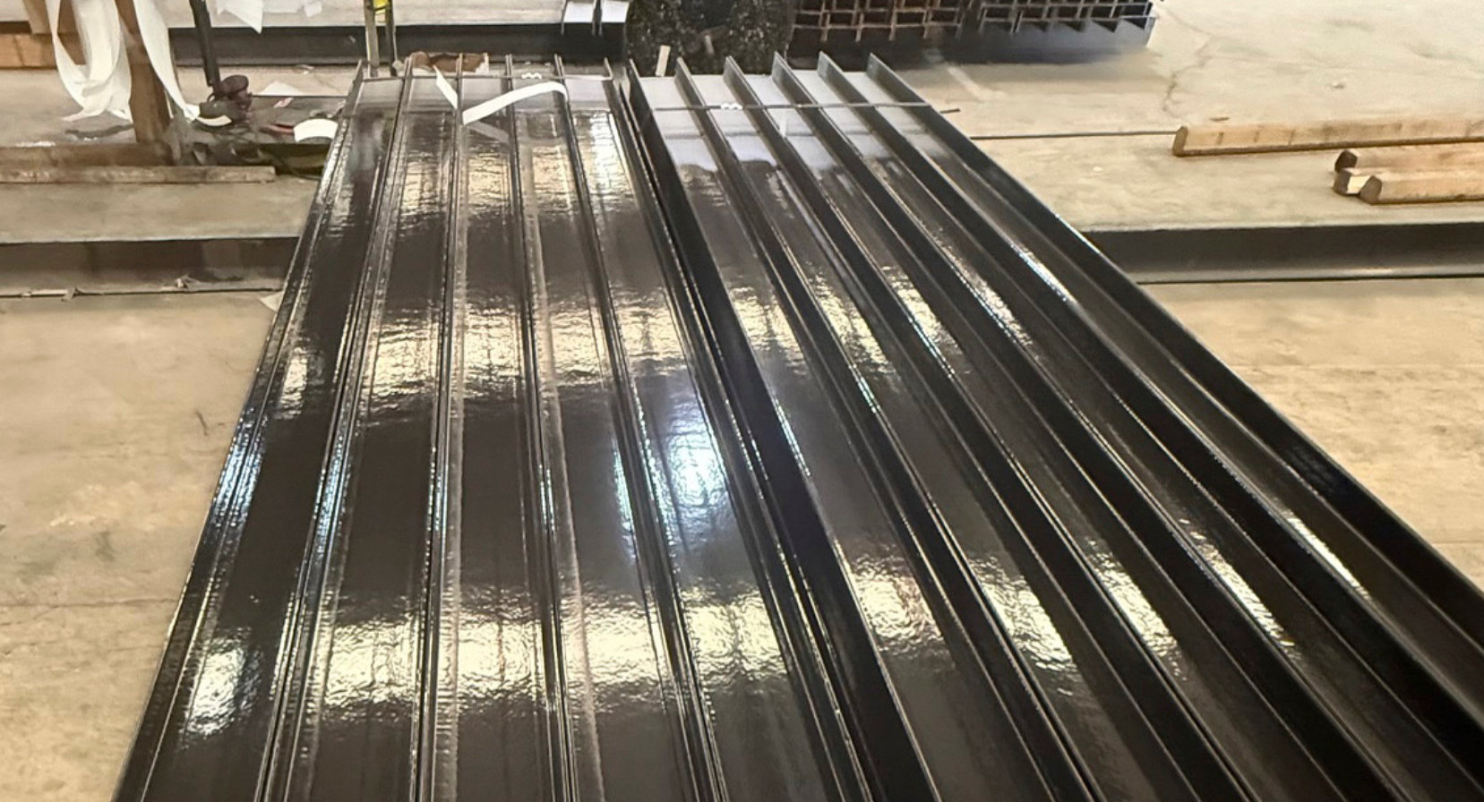  Close view of steel piles with a smooth, glossy black protective coating.