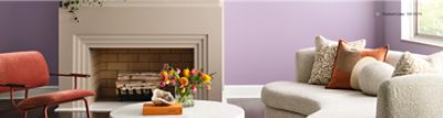 Living room painted Radiant Lilac with a large fireplace and a cream sofa.