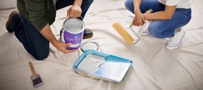 Two people pouring paint inside a paint tray