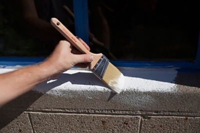 A man painting white trim onto a garage