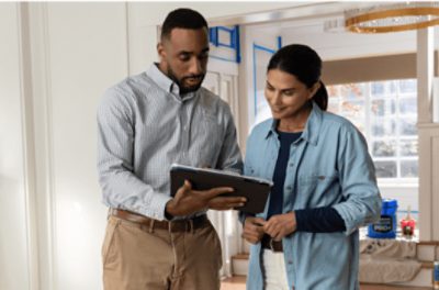 Two people standing and looking at a tablet.