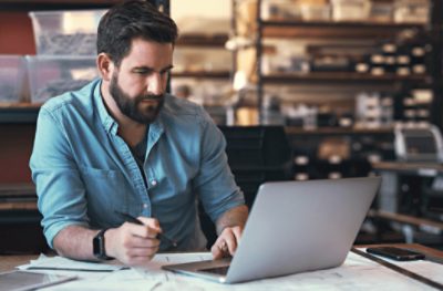 A person using a laptop and taking notes.