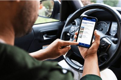 Person in driver's seat on mobile phone using Sherwin-Williams project bids.