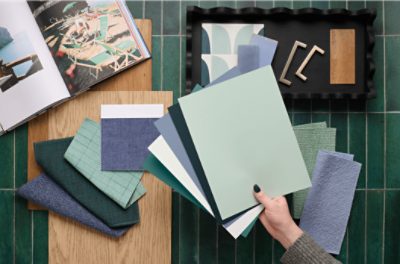 A person holding samples over a table with design elements and inspiration.