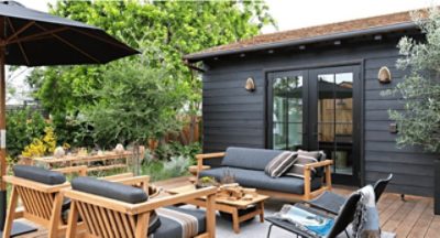 A stained wood deck with furniture and black painted French doors leading inside.