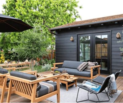 A stained wood deck with furniture and black painted French doors leading inside.