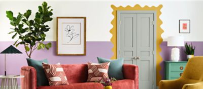 Living room with Radiant Lilac feature wall, Kingdom Gold door frame design, and colorful furniture.