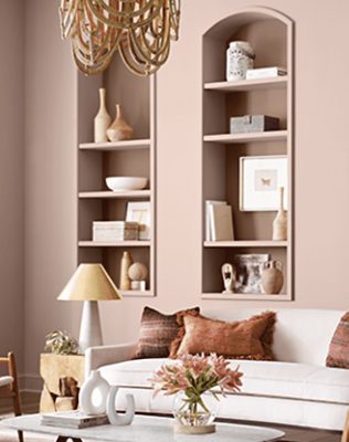 Neutral living room with shelves filled with decor and a tan couch.