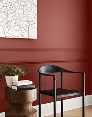 Red walls with print, wooden chair with side table and decor..