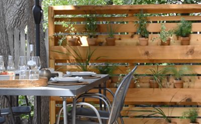 An outdoor floating planter wall next to a metal table set for four.