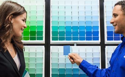 A Sherwin-Williams employee showing a customer a paint chip.