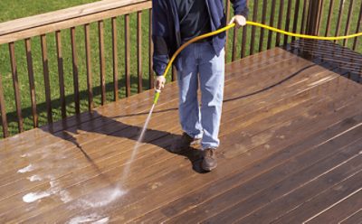 A person cleaning a wood deck.