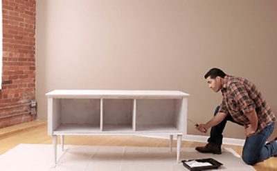 A person priming a piece of furniture.