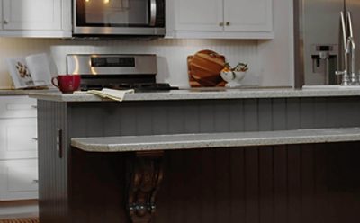 A kitchen with white cabinets, a black wood paneled island, and hardwood floors.